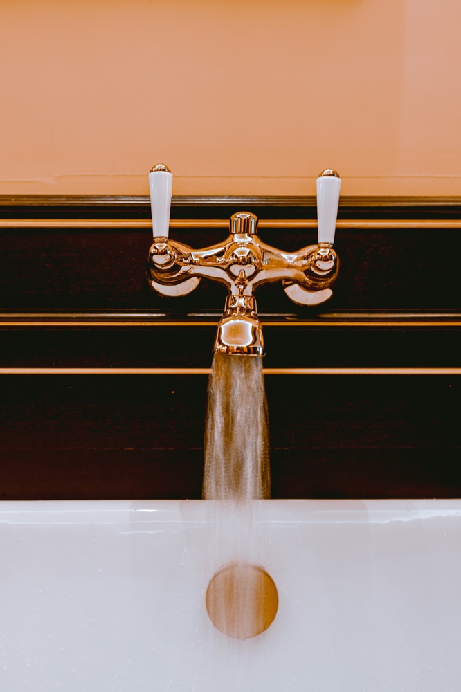 Brass crosshead taps running into a white basin
